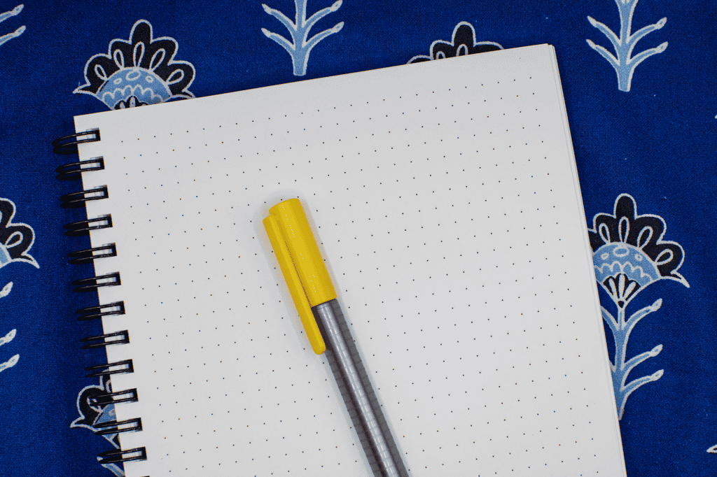 Notes and planner with yellow pen on colorful decorative background for organization and planning.